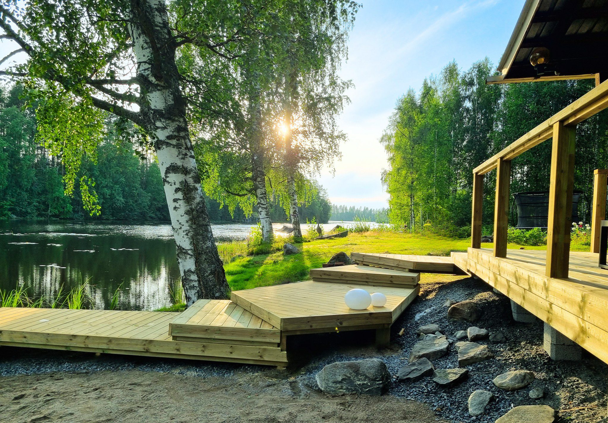 Rauhallisen ulkoilman luovat puinen terassi ja portaat rauhallisella järvenrannalla, jota ympäröivät vihreät puut ja auringonvalo. Kaksi pyöreää valkoista valoa istuu kannella, esittelemällä seesteistä ympäristöä - täydellinen rentoutumiseen jr pihahuollon jälkeen. | JR Pihahuolto Oy, Kuopio Rauhallisen ulkoilman luovat puinen terassi ja portaat rauhallisella järvenrannalla, jota ympäröivät vihreät puut ja auringonvalo. Kaksi pyöreää valkoista valoa istuu kannella, esittelemällä seesteistä ympäristöä - täydellinen rentoutumiseen jr pihahuollon jälkeen. | JR Pihahuolto Oy, Kuopio